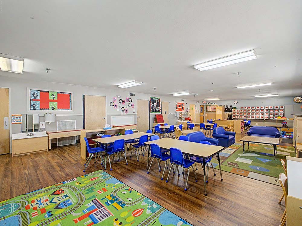 Classroom with small tables, chairs, and play areas