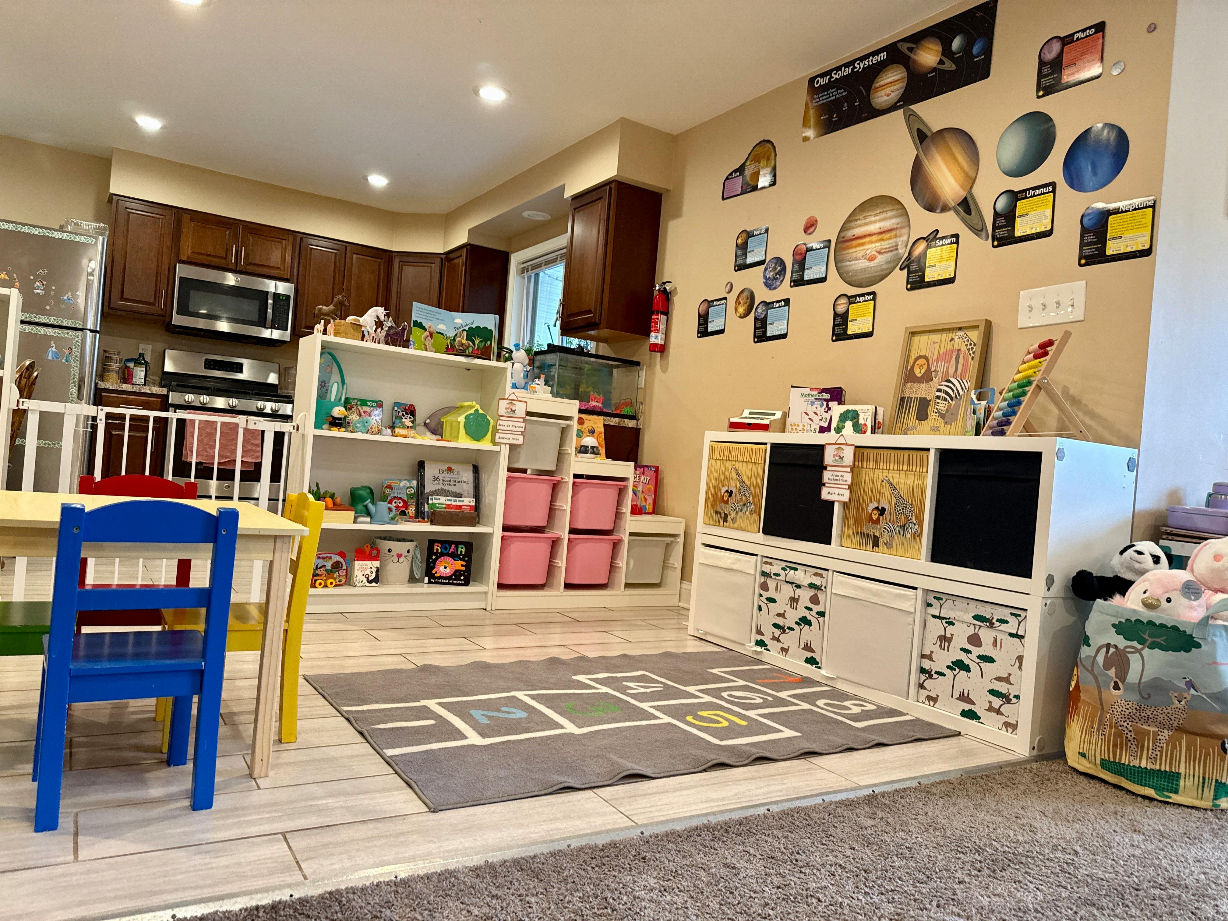 Childcare room with play kitchen, toy storage, and a hopscotch mat