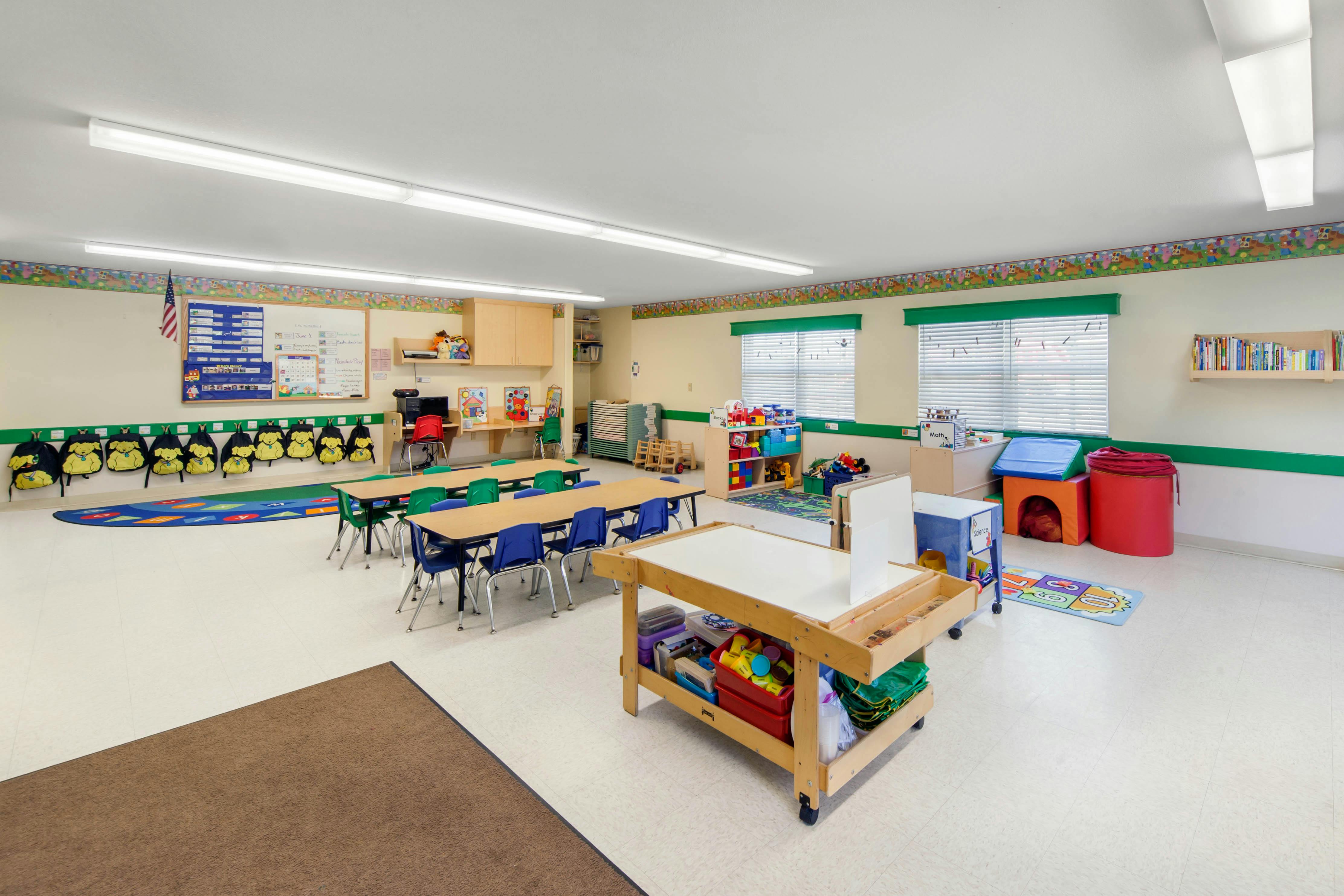 Empty colorful children's classroom with tables and chairs, whiteboards, and storage
