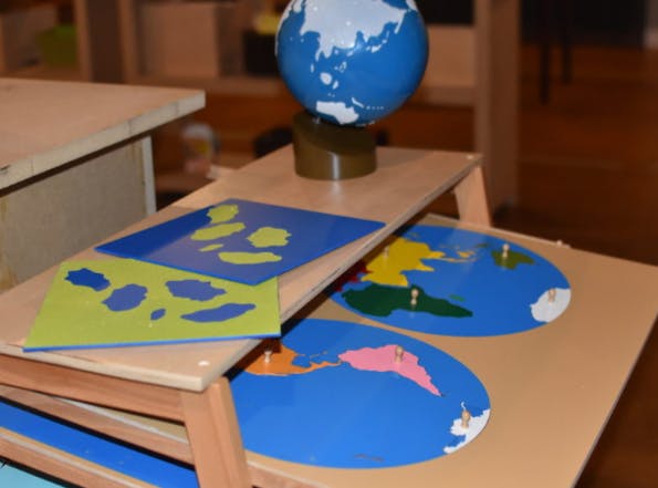 Montessori geography materials including a globe and puzzle maps