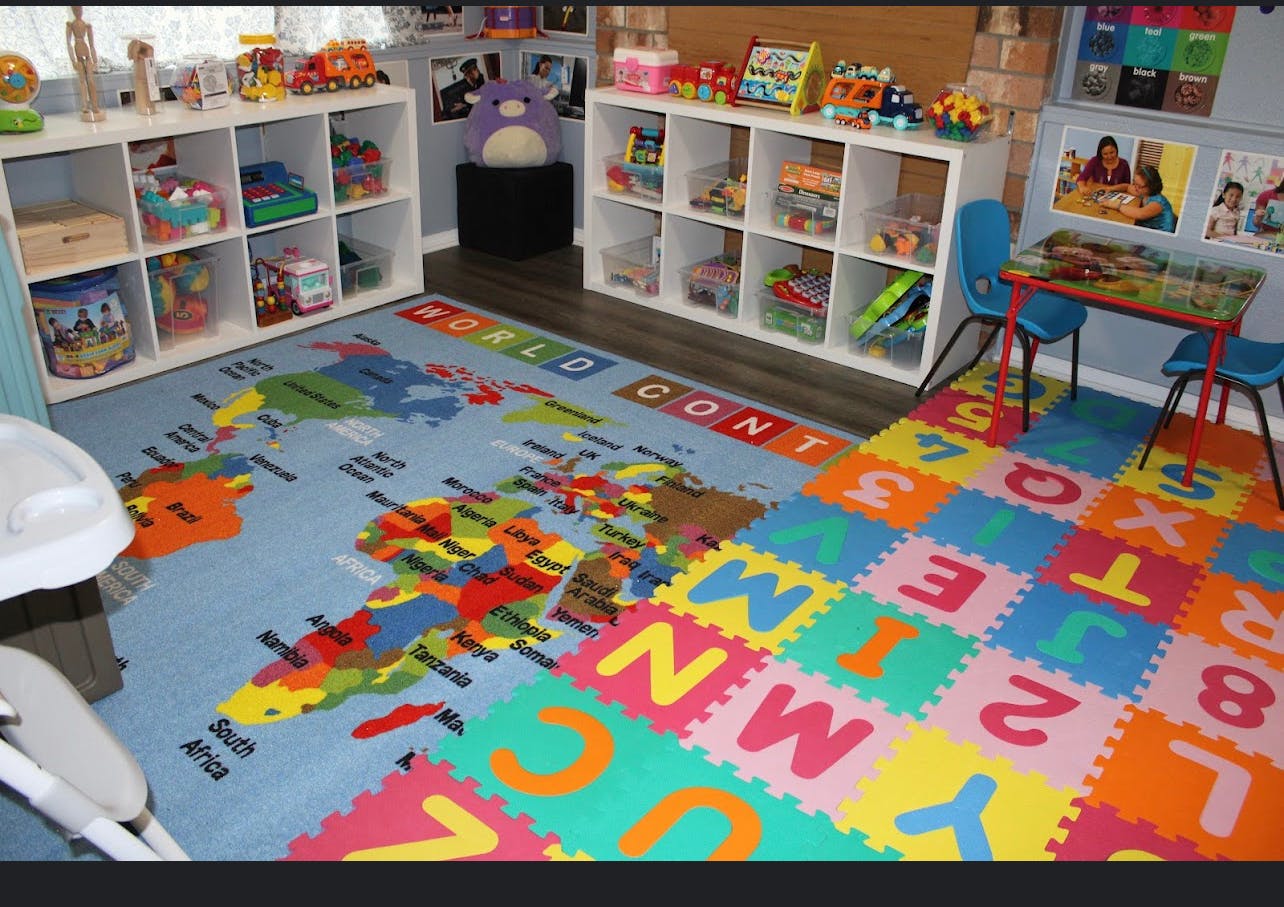 Playroom with world map rug, alphabet floor mats, and shelves of toys
