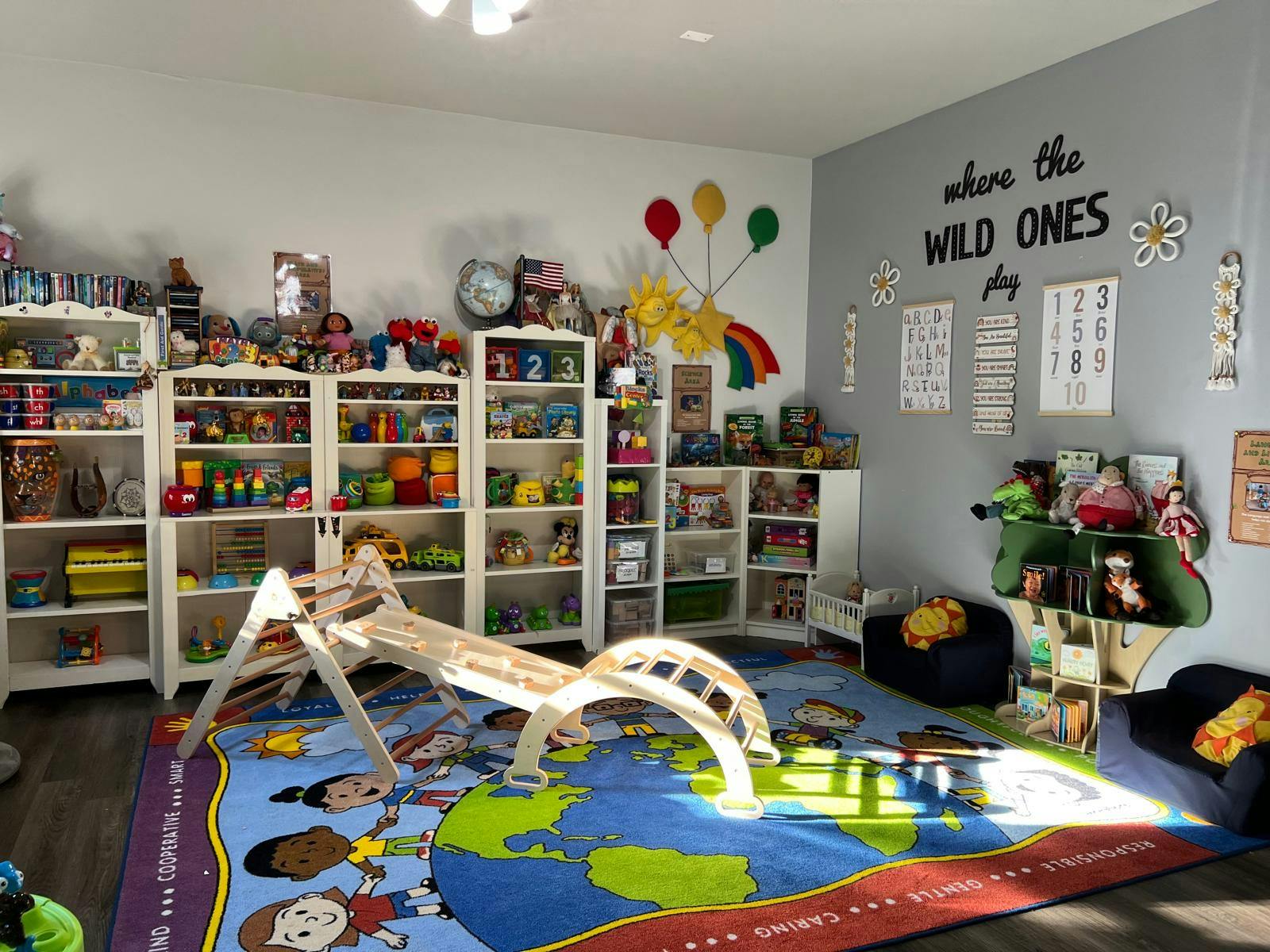 Playroom with shelves of toys, a climbing structure, and a world map rug