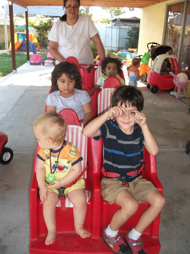 Person pushing a multi-child stroller with four children seated