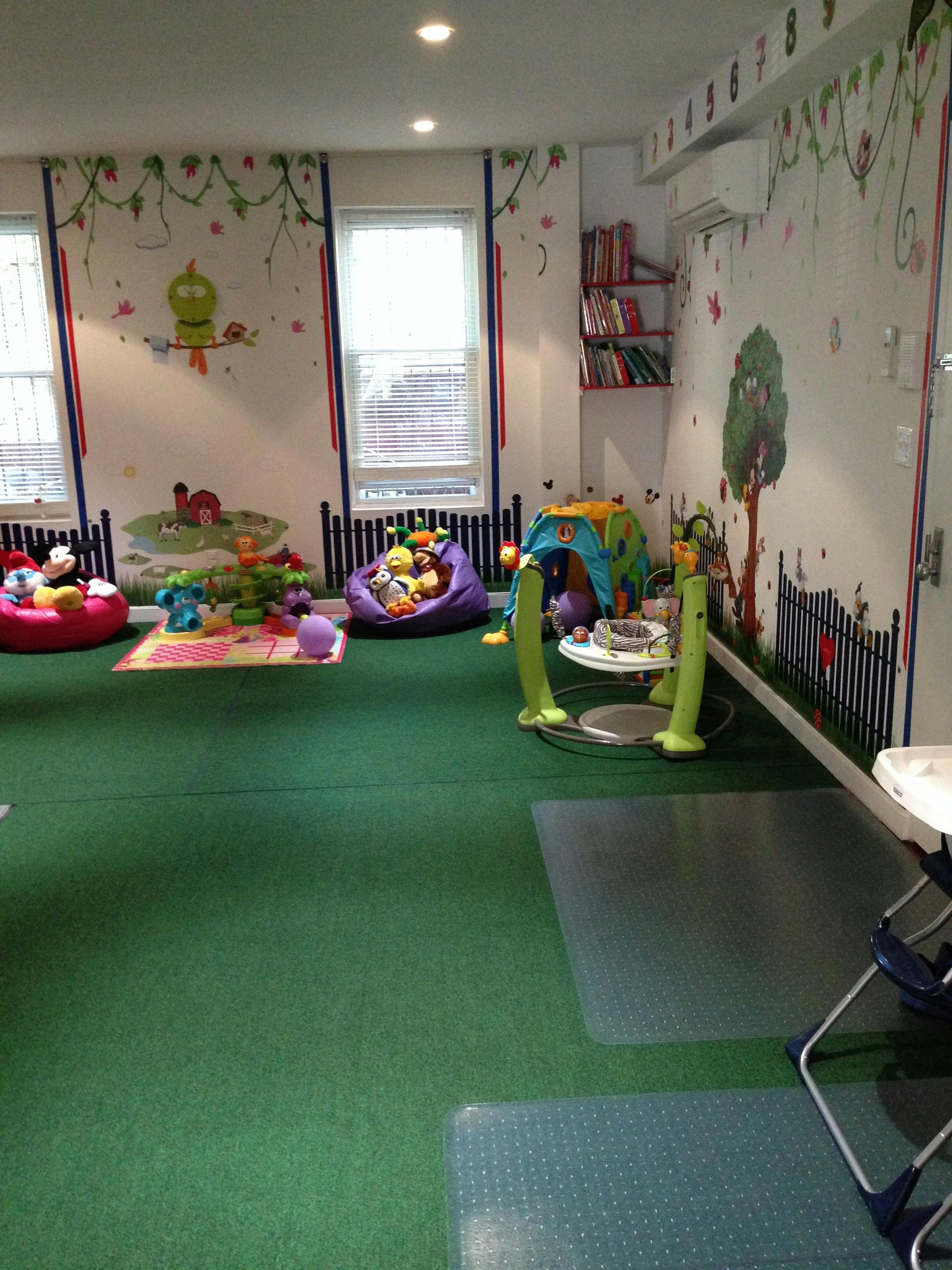 Playroom with green carpet, toys, and wall murals