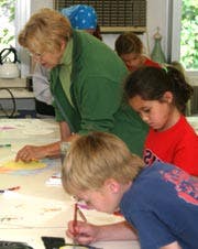 Adult and children drawing at a table