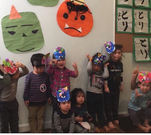 Group of children wearing paper hats and masks in a classroom