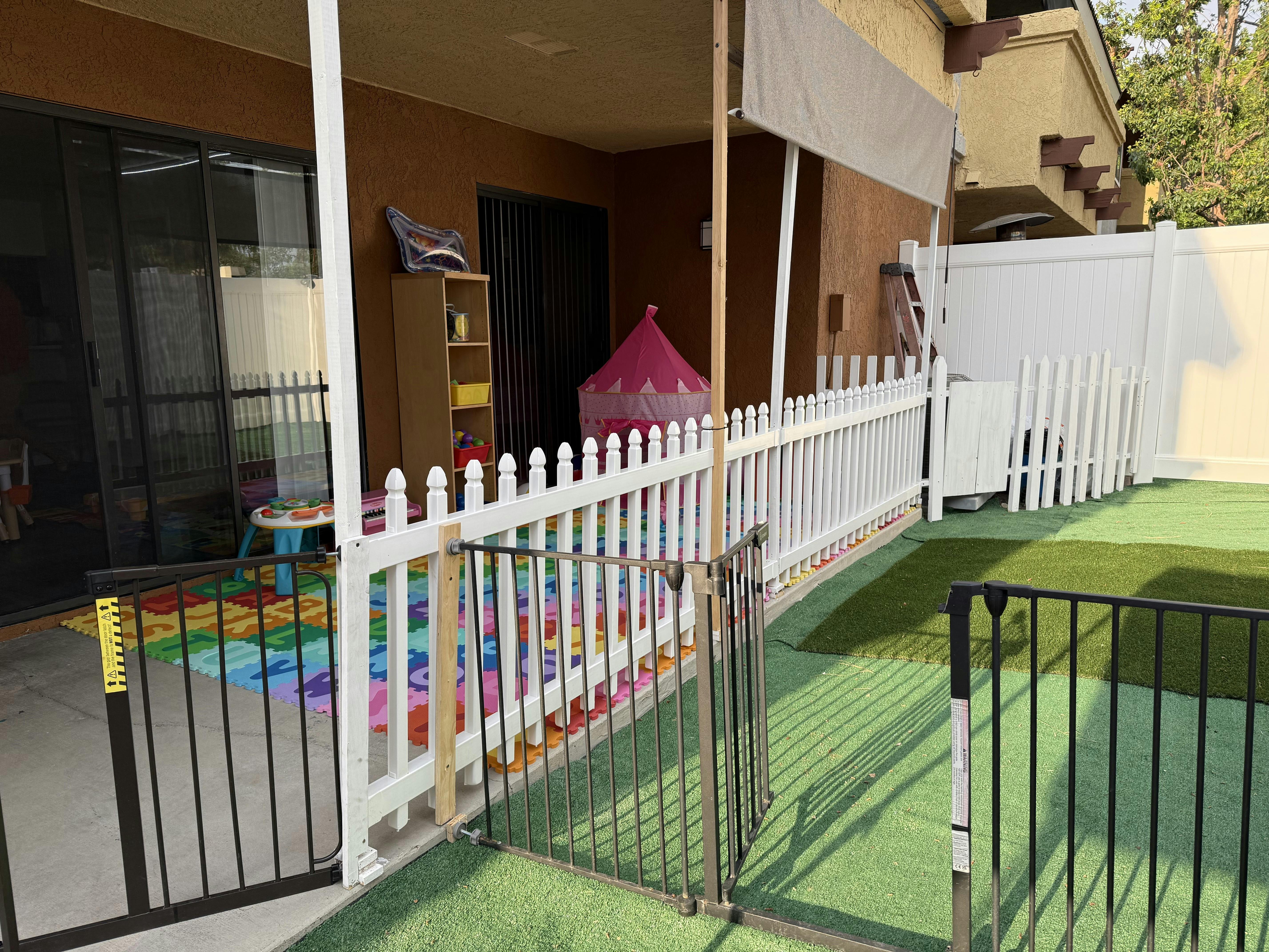 Outdoor play area with an artificial turf lawn separated by a white picket fence