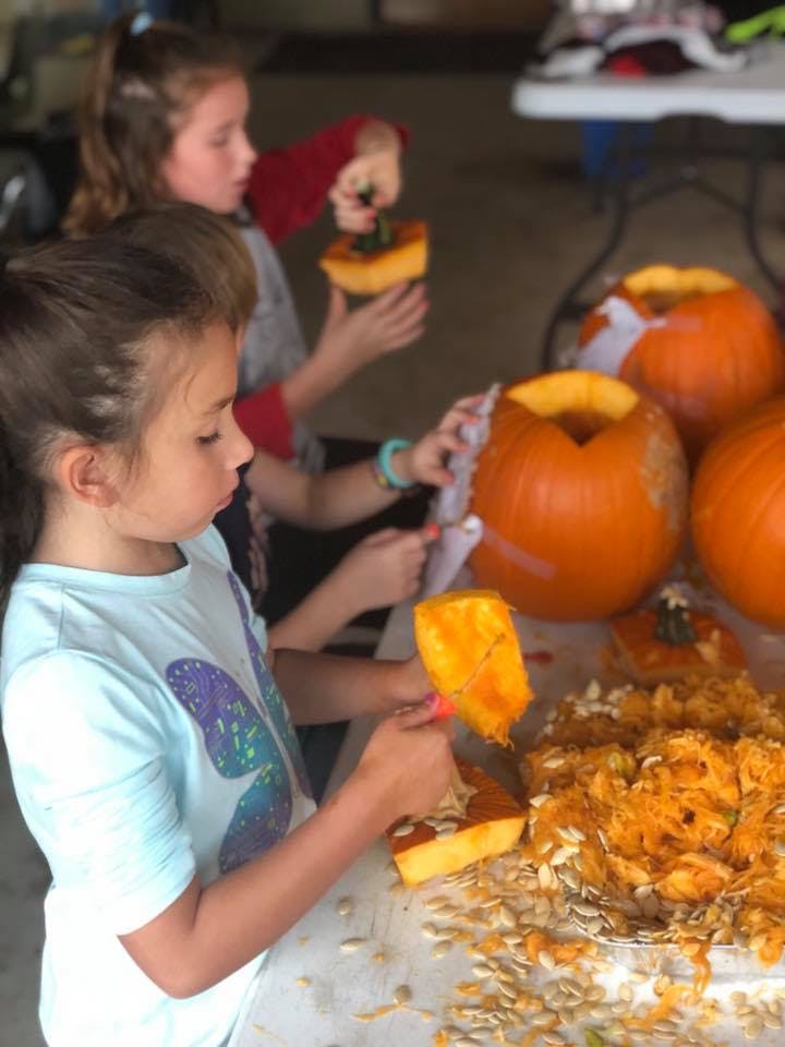 Children carving pumpkins, removing seeds and pulp