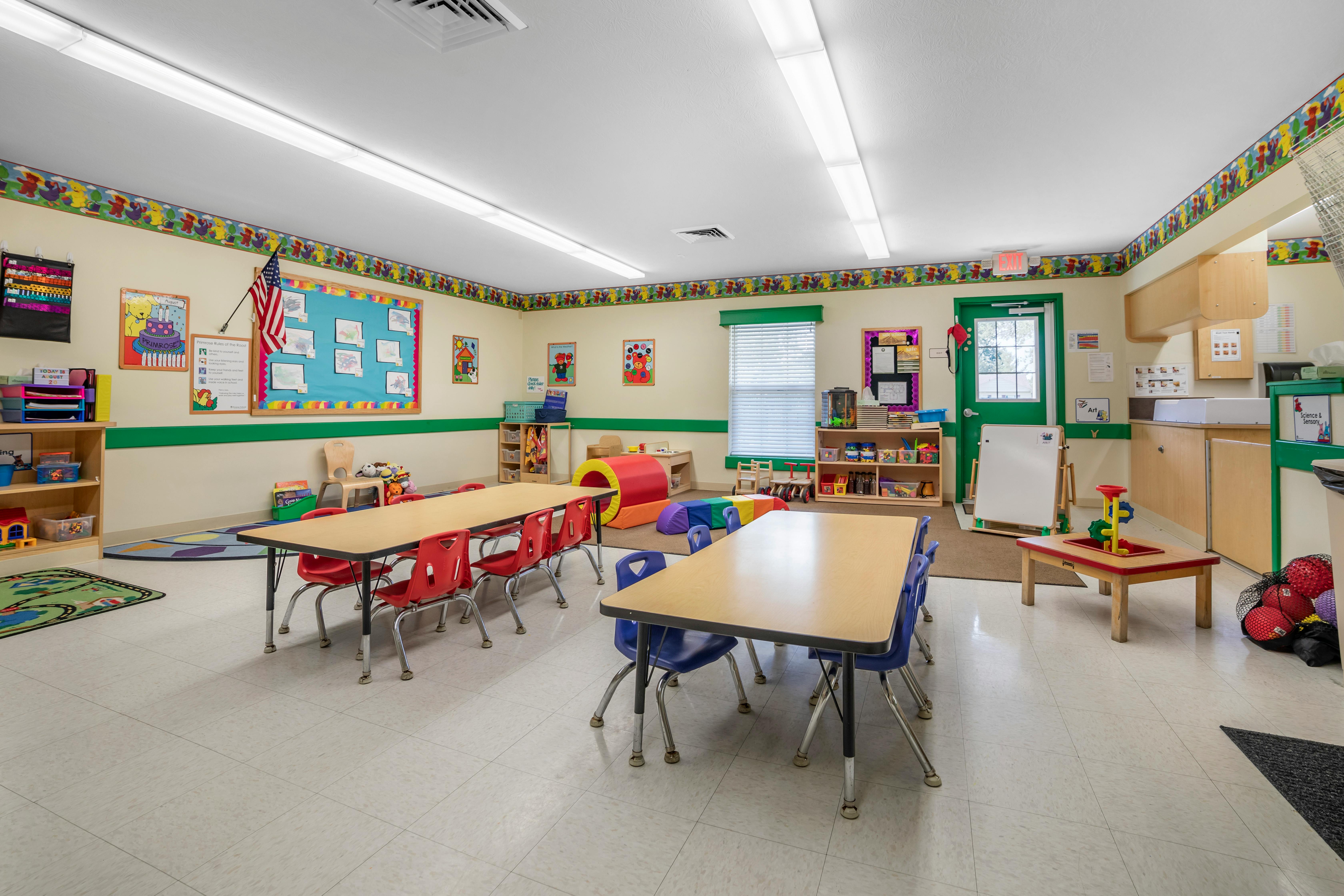 Empty colorful preschool classroom with small tables and chairs