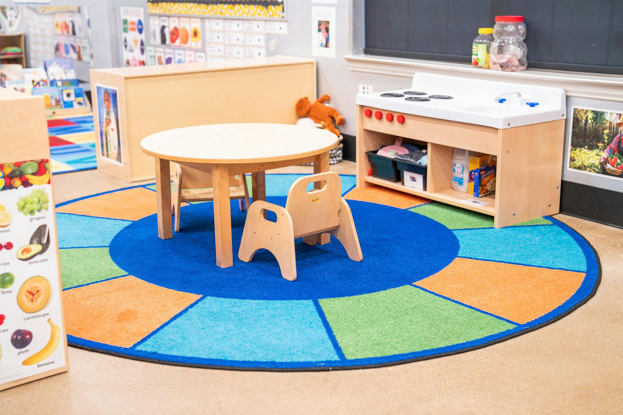 Small round table and chairs in a classroom with a play kitchen