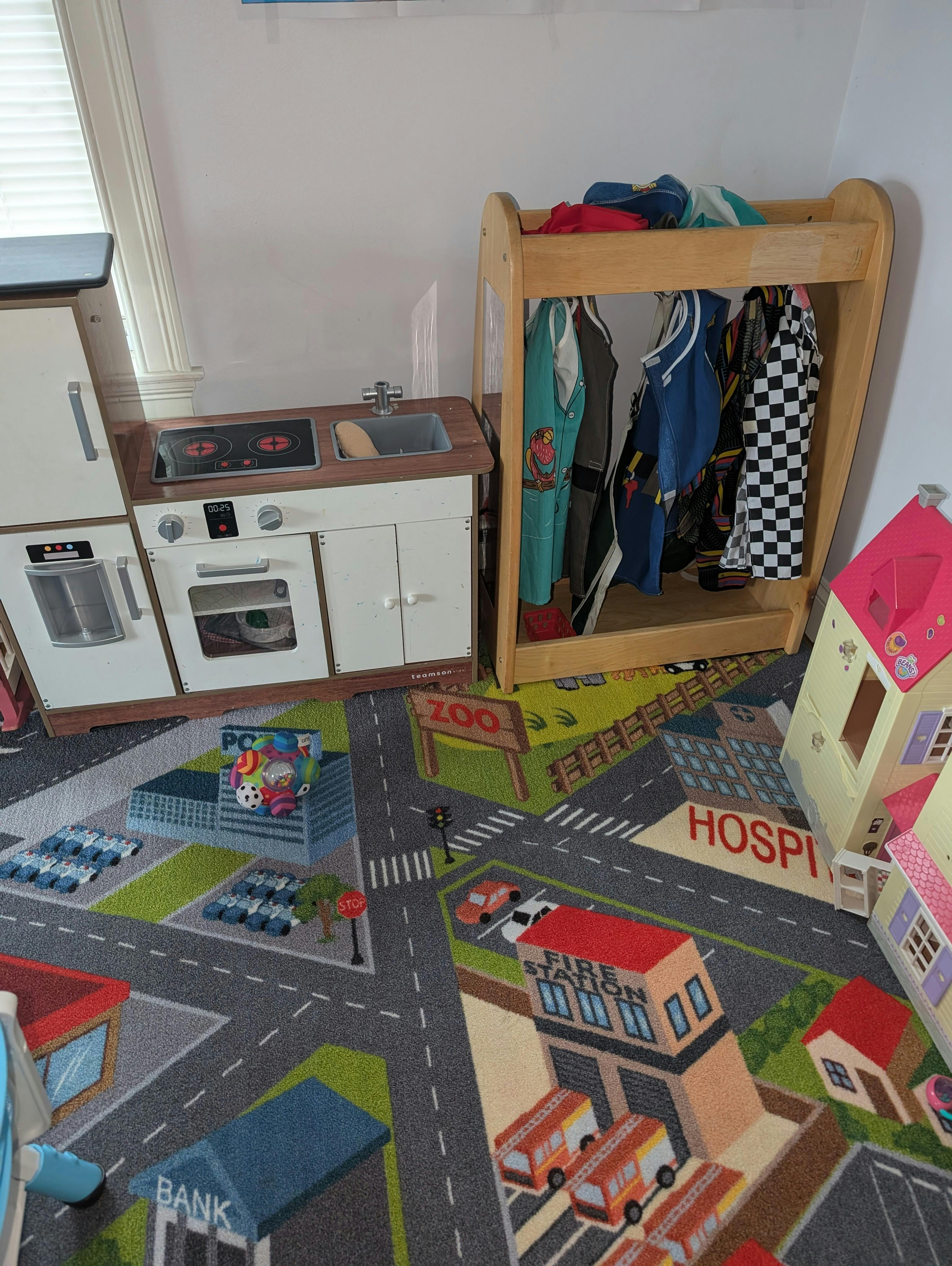 Play kitchen and clothing rack on a city-themed rug