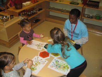 Adult and three children doing an art activity at a table