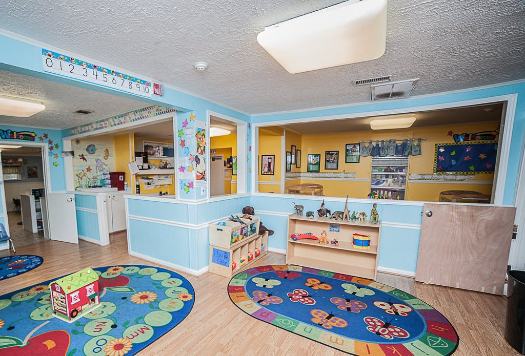 Playroom with blue and yellow walls, colorful rugs, and toys