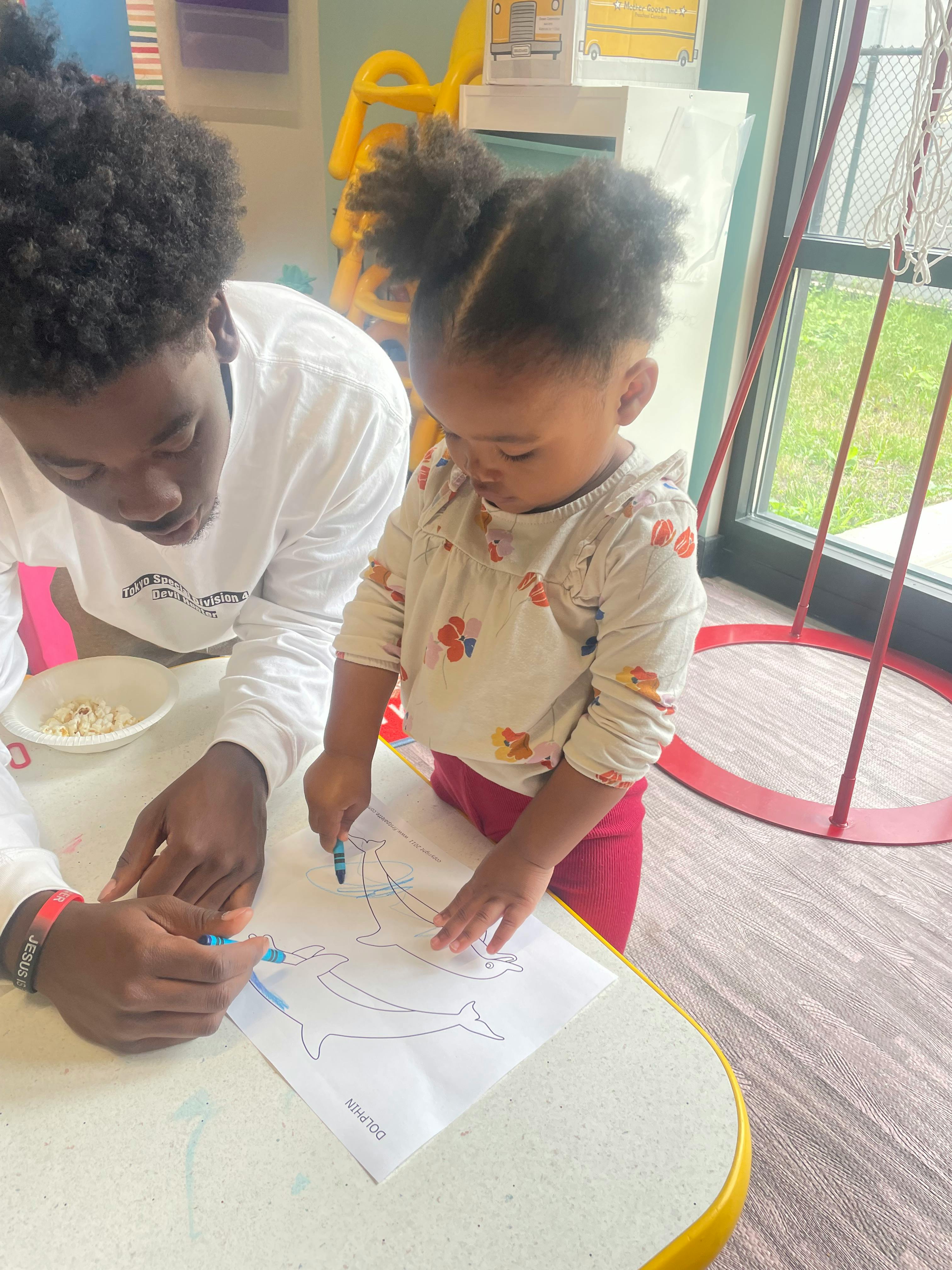 Person and child coloring a dolphin outline on paper