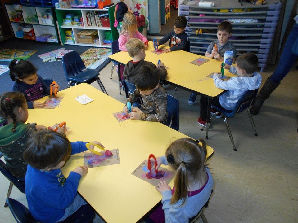 Children sitting at tables and drawing in a classroom