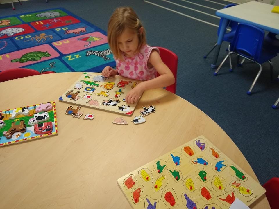 Child playing with a wooden puzzle at a table