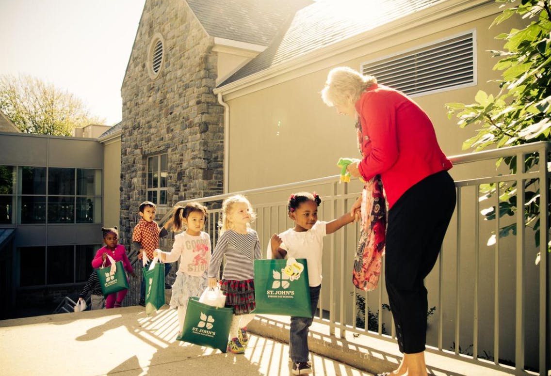 Adult handing items to children holding green bags