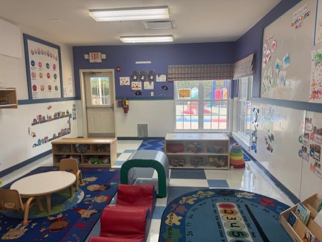 Empty colorful preschool classroom with tables, chairs, and rugs