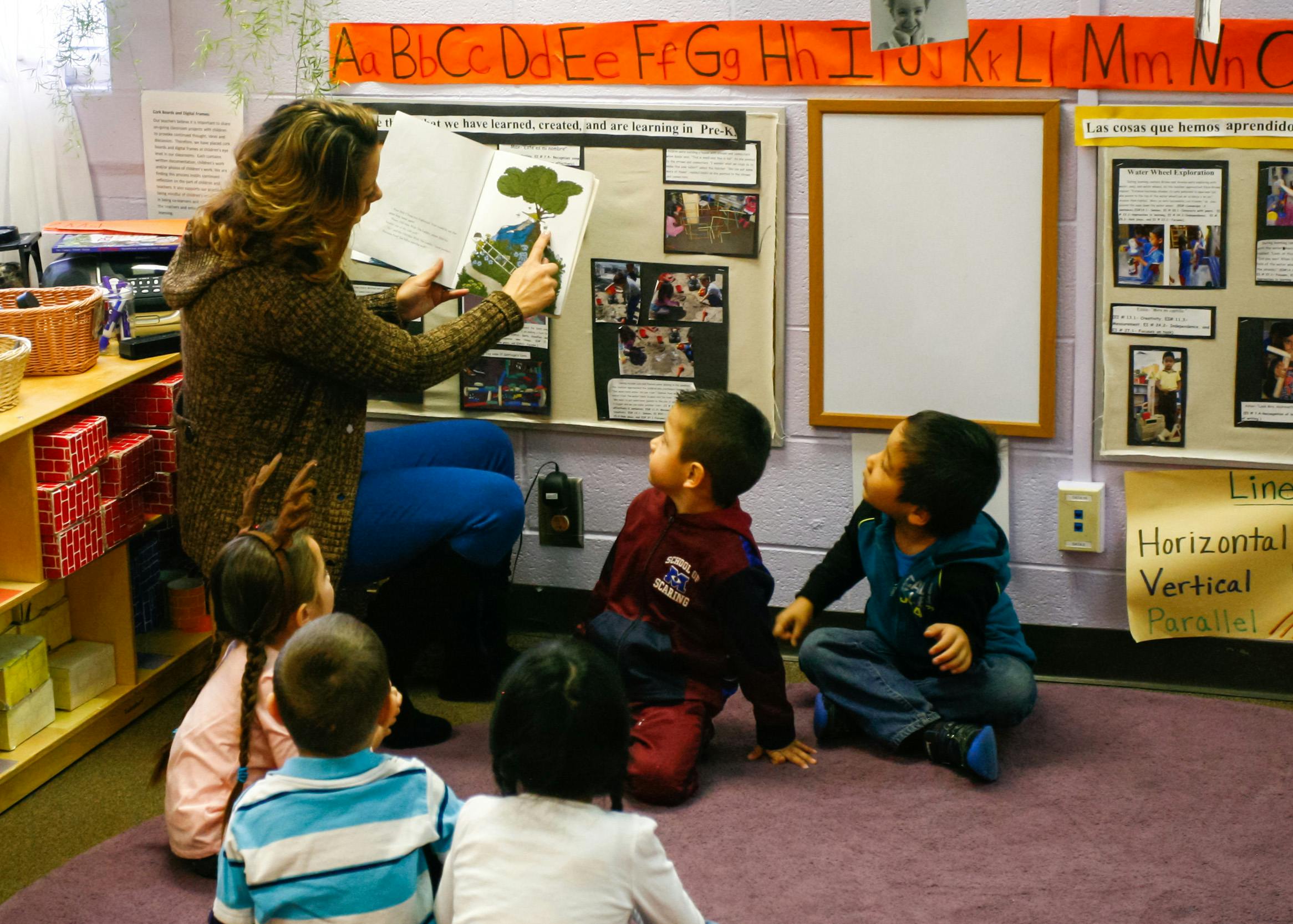 Person reading a book to children in a classroom