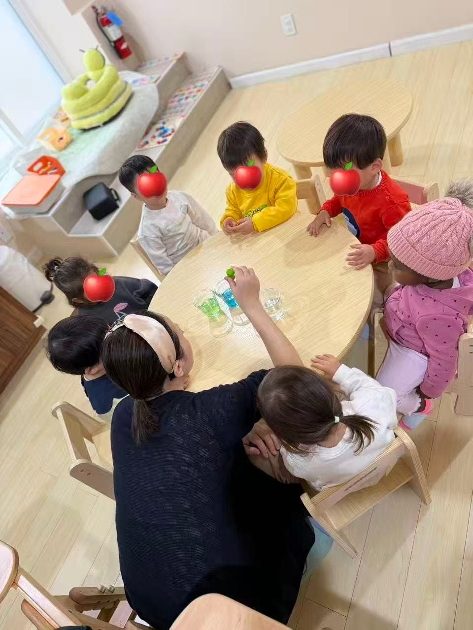 Adult and children at a table with cups, possibly doing an experiment