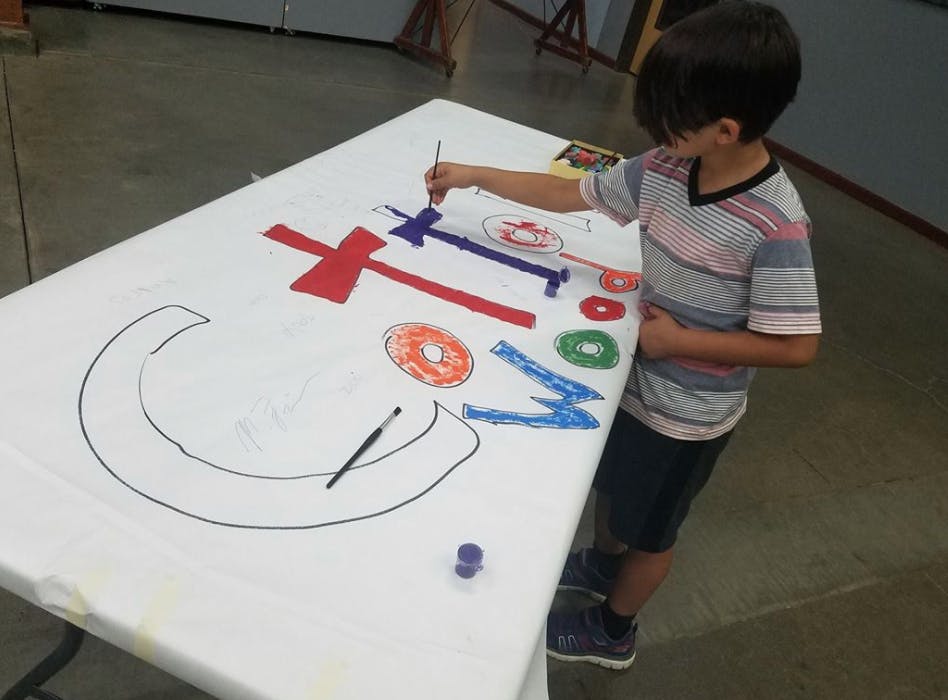 Child painting on a large white sheet of paper