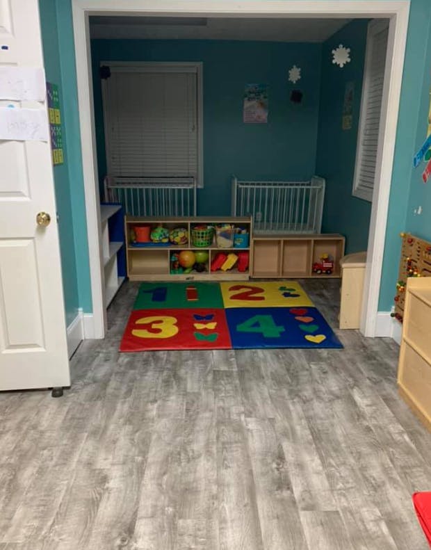 Playroom with cribs, toy shelves, and a colorful number mat