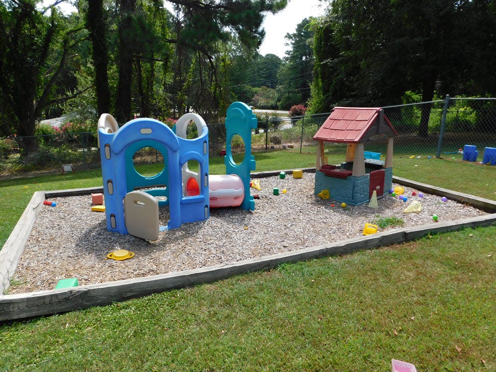 Outdoor playground with play structure and small playhouse on wood chips