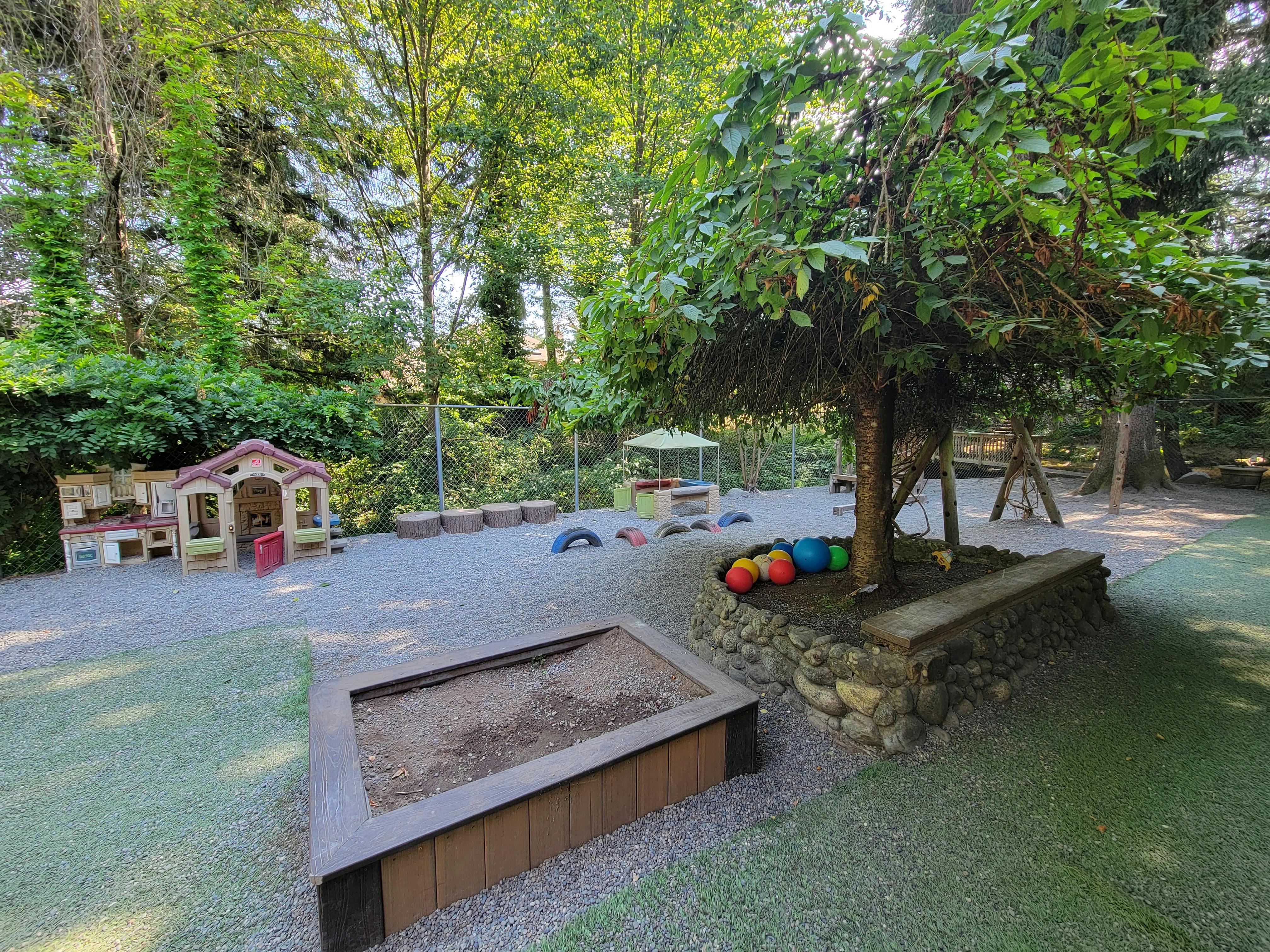 Outdoor playground with sandbox, playhouse, and tree