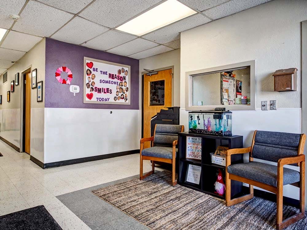 Lobby with two chairs, an aquarium, and a bulletin board that says "Be the reason someone smiles today"