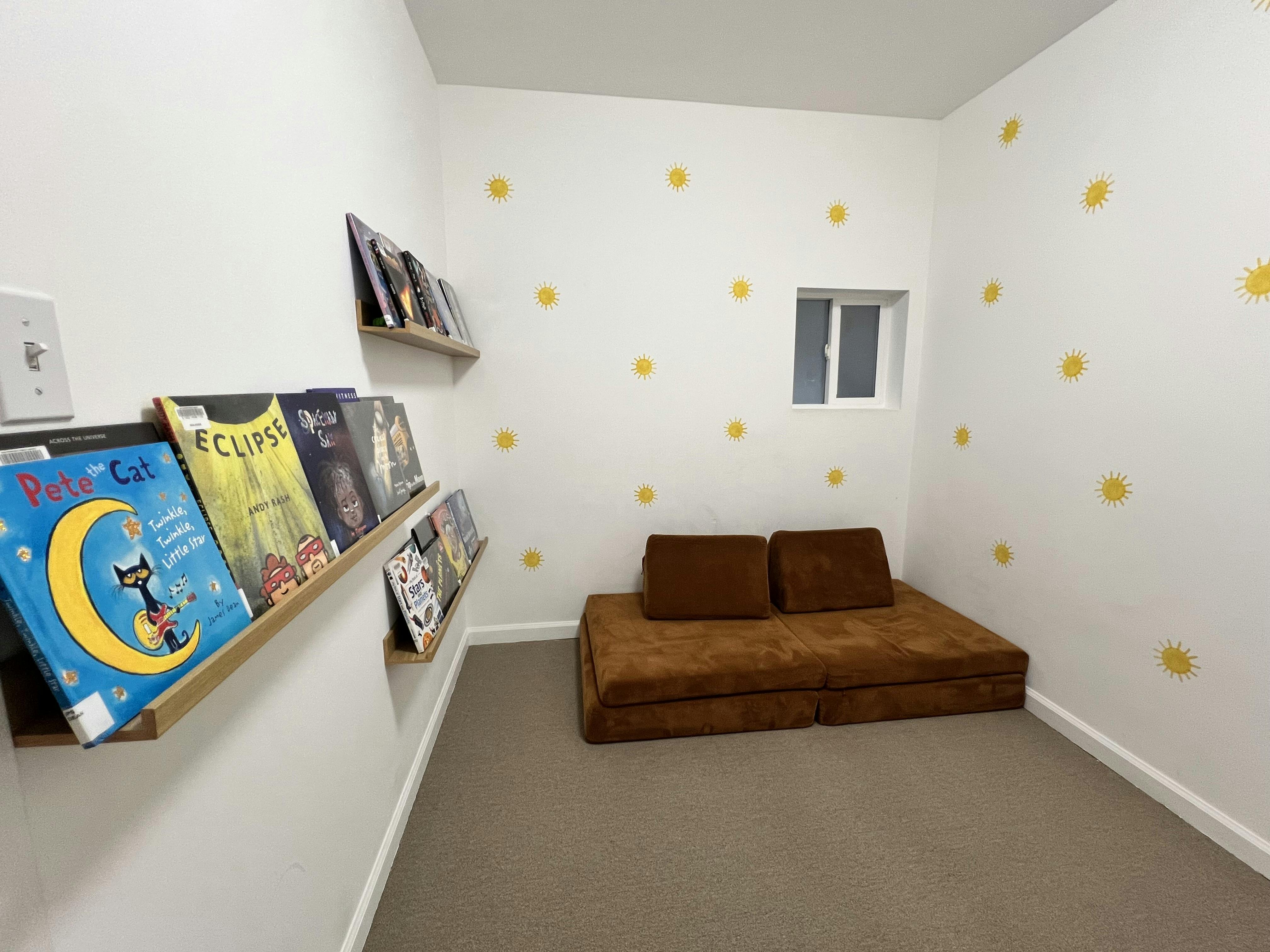 Reading nook with floor cushions and children's books on floating wall shelves