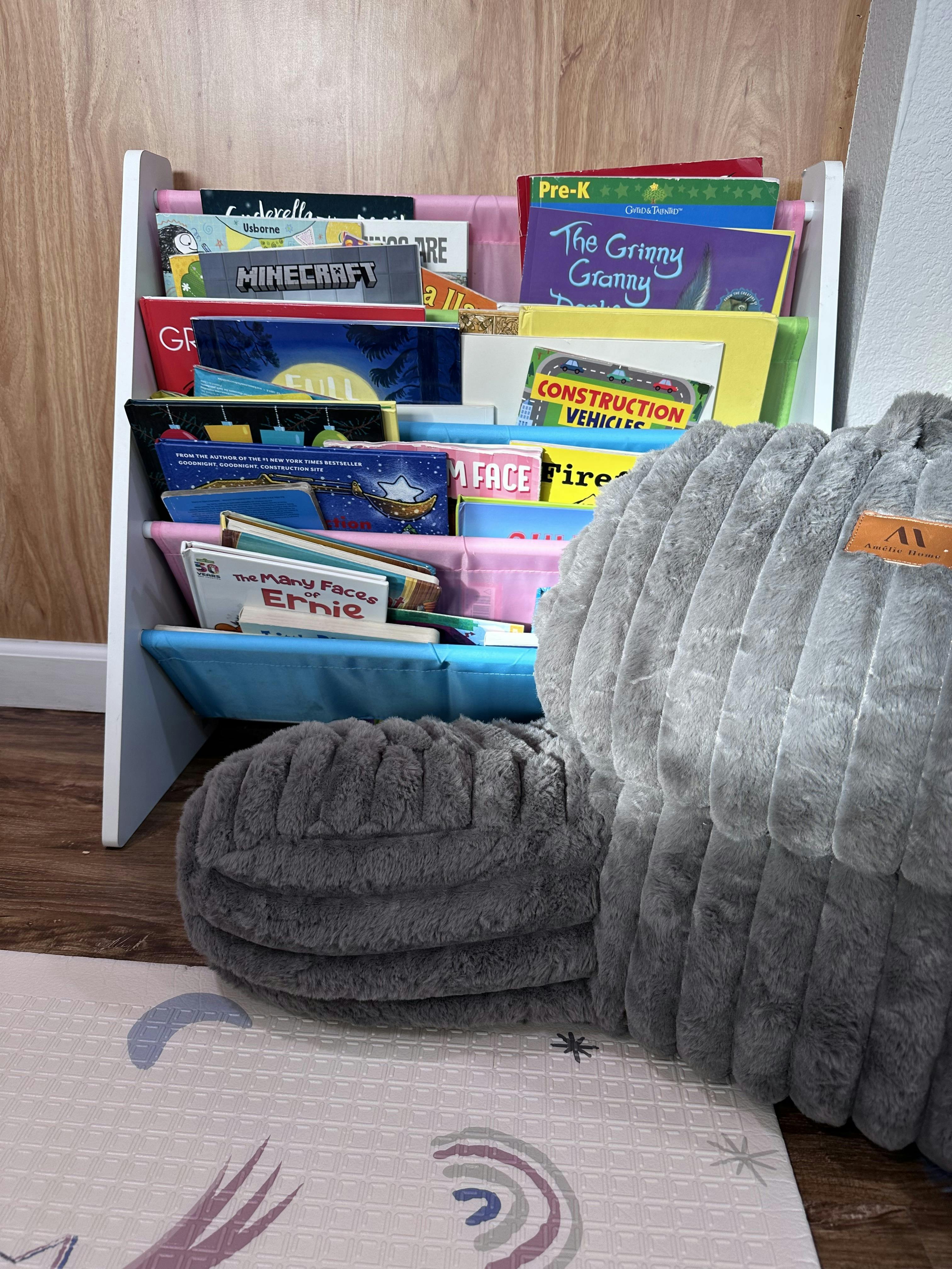 child's bookshelf filled with various picture books, next to a soft gray pillow