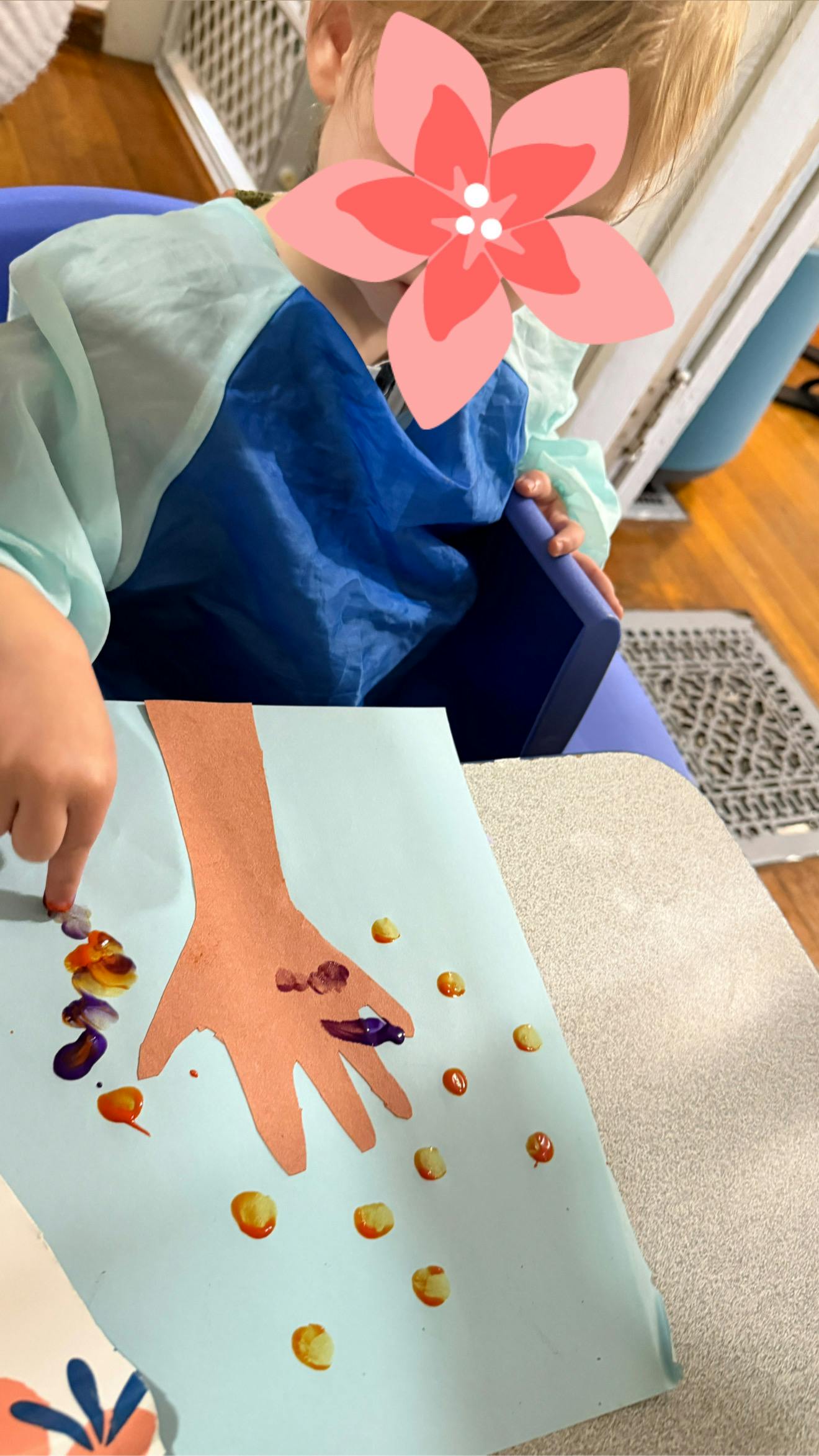 Child finger painting on a paper cutout of a hand