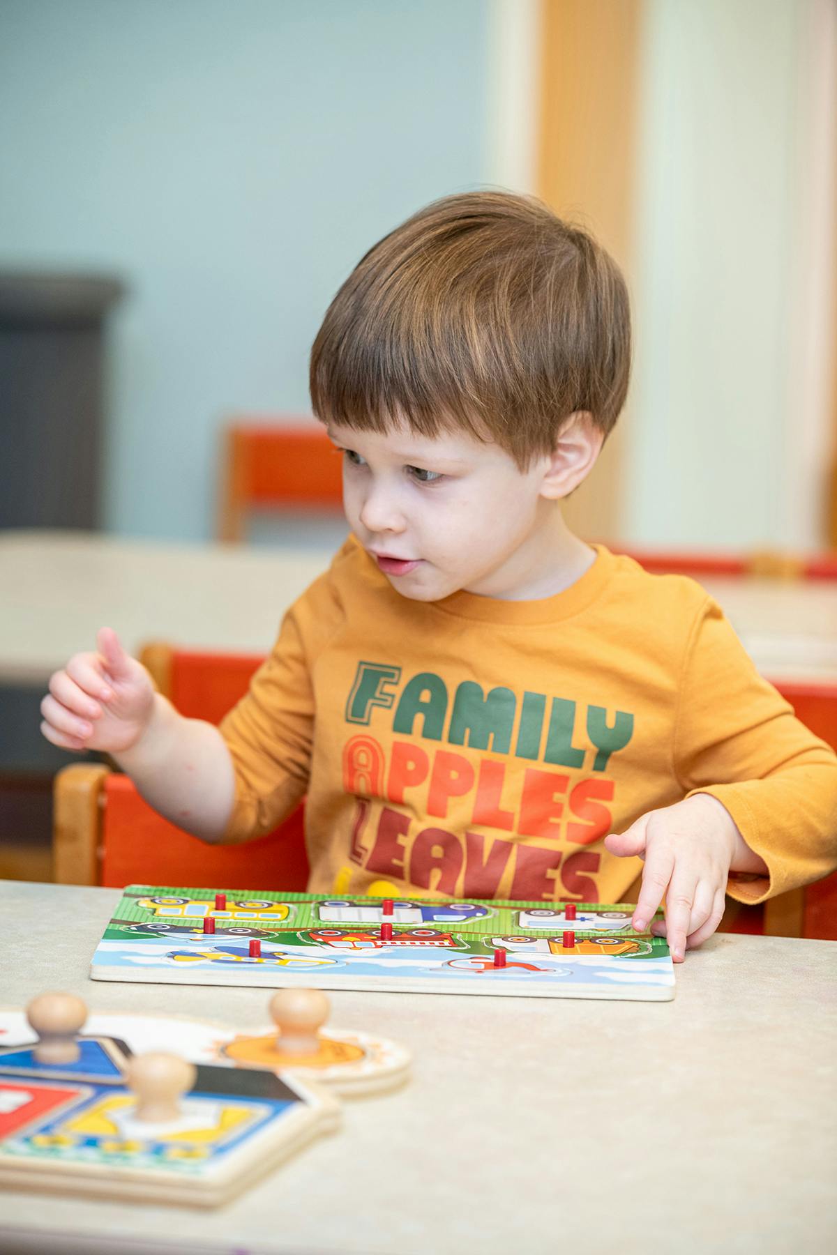 Child playing with a peg board game at a table