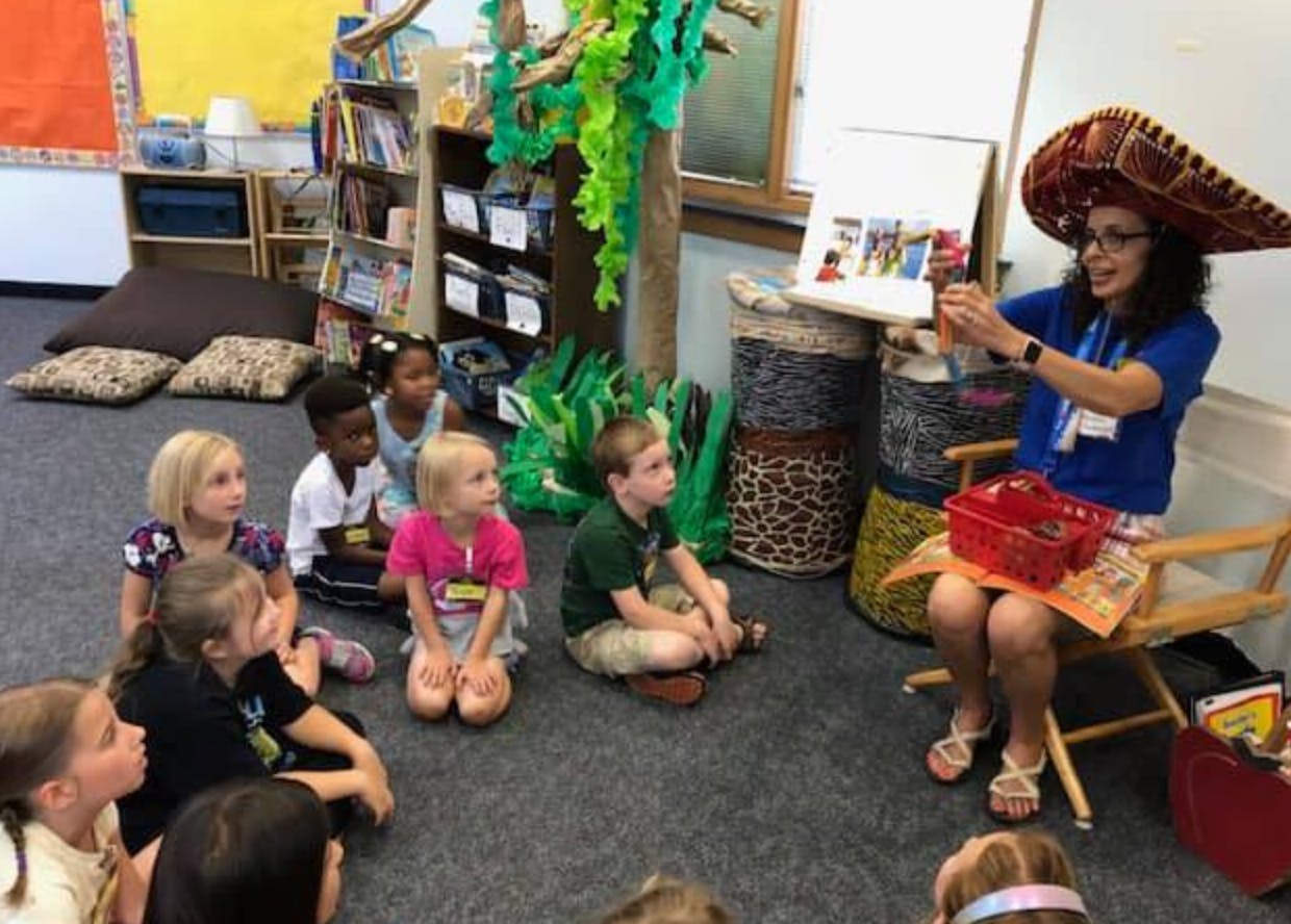 Person in sombrero reading to children in a classroom