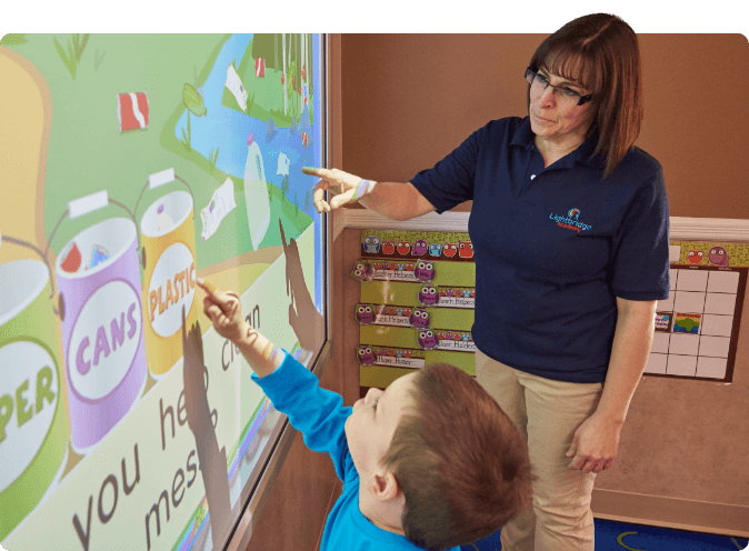 Adult and child pointing at an interactive screen with recycling graphics