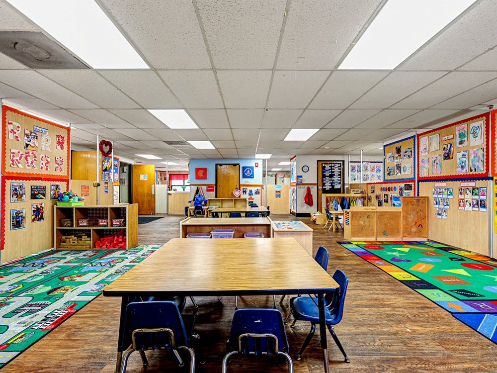 empty classroom with tables, chairs, and colorful rugs