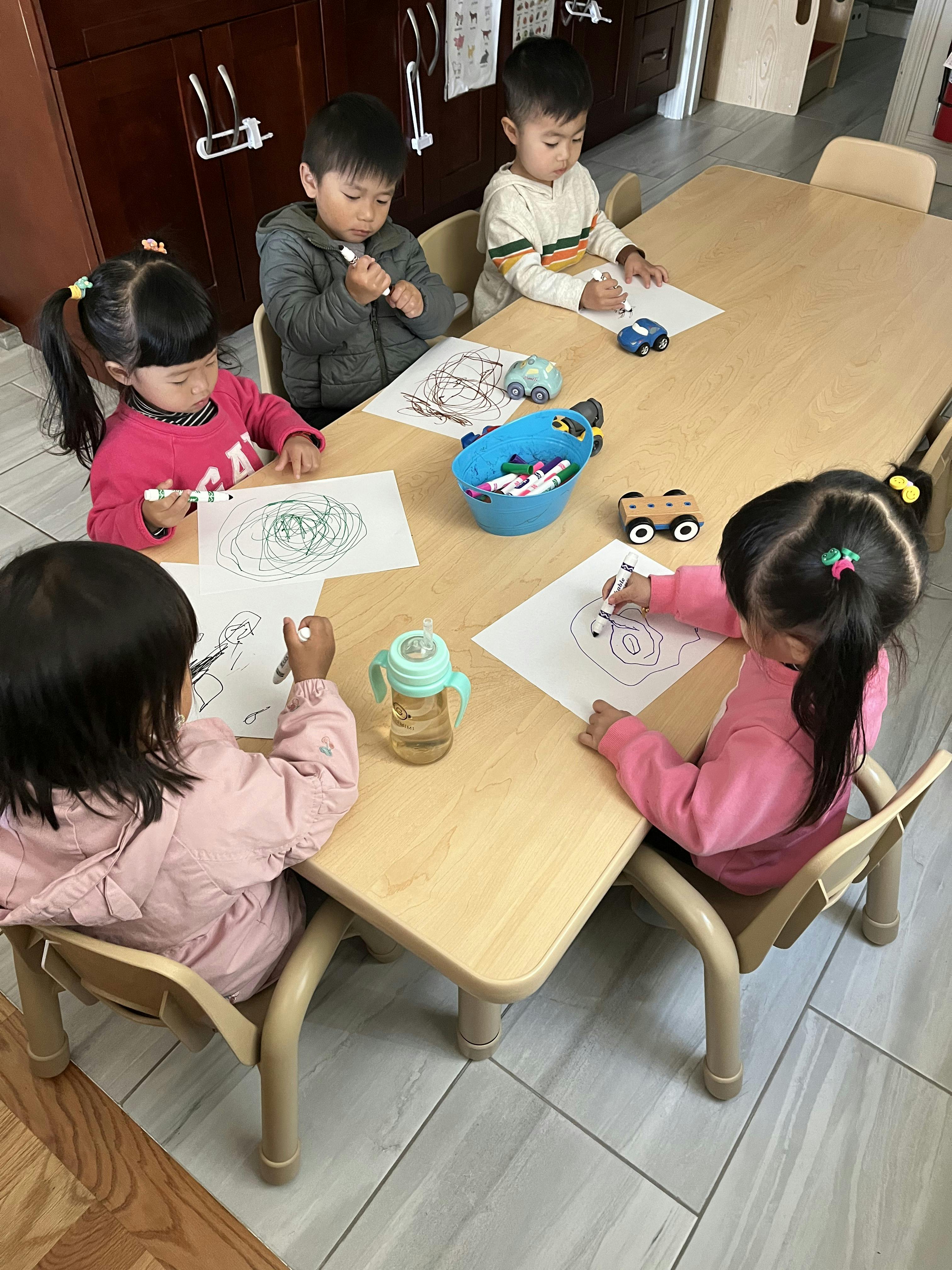 Four children drawing at a table