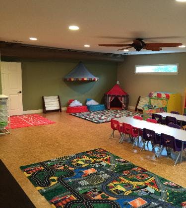 Playroom with small tables and chairs, play tents, and colorful rugs