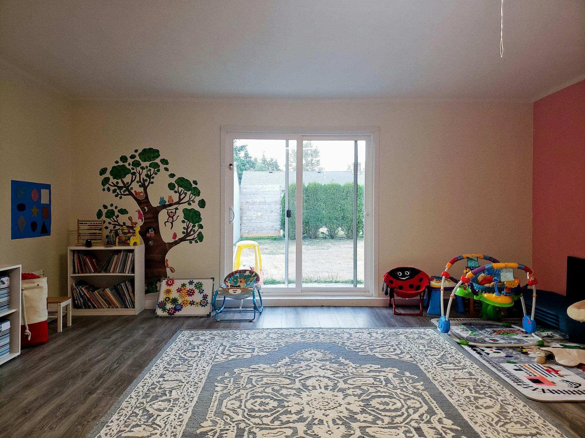 Playroom with a tree wall decal, bookshelves, and toys