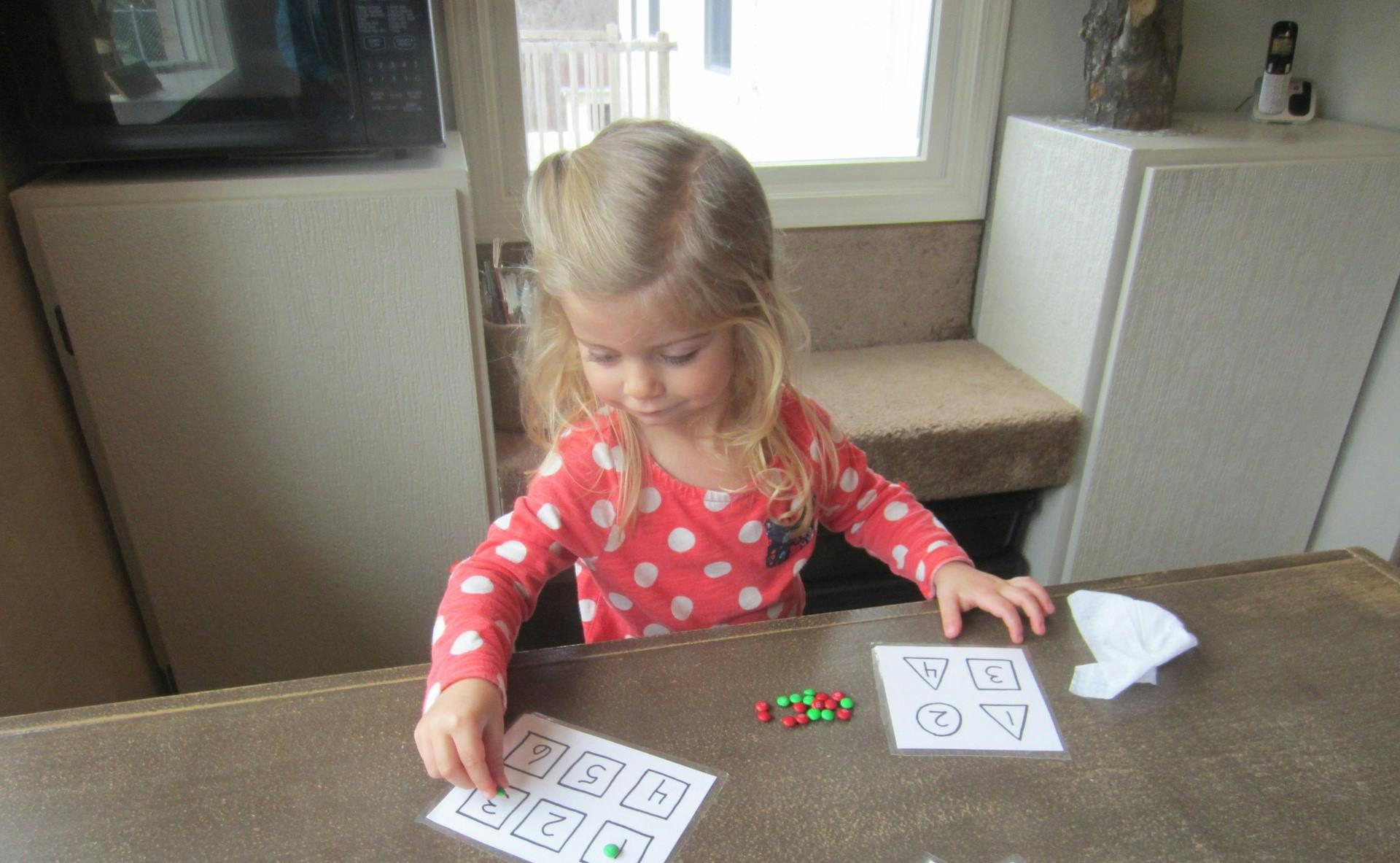 Child playing with cards and small objects on a table