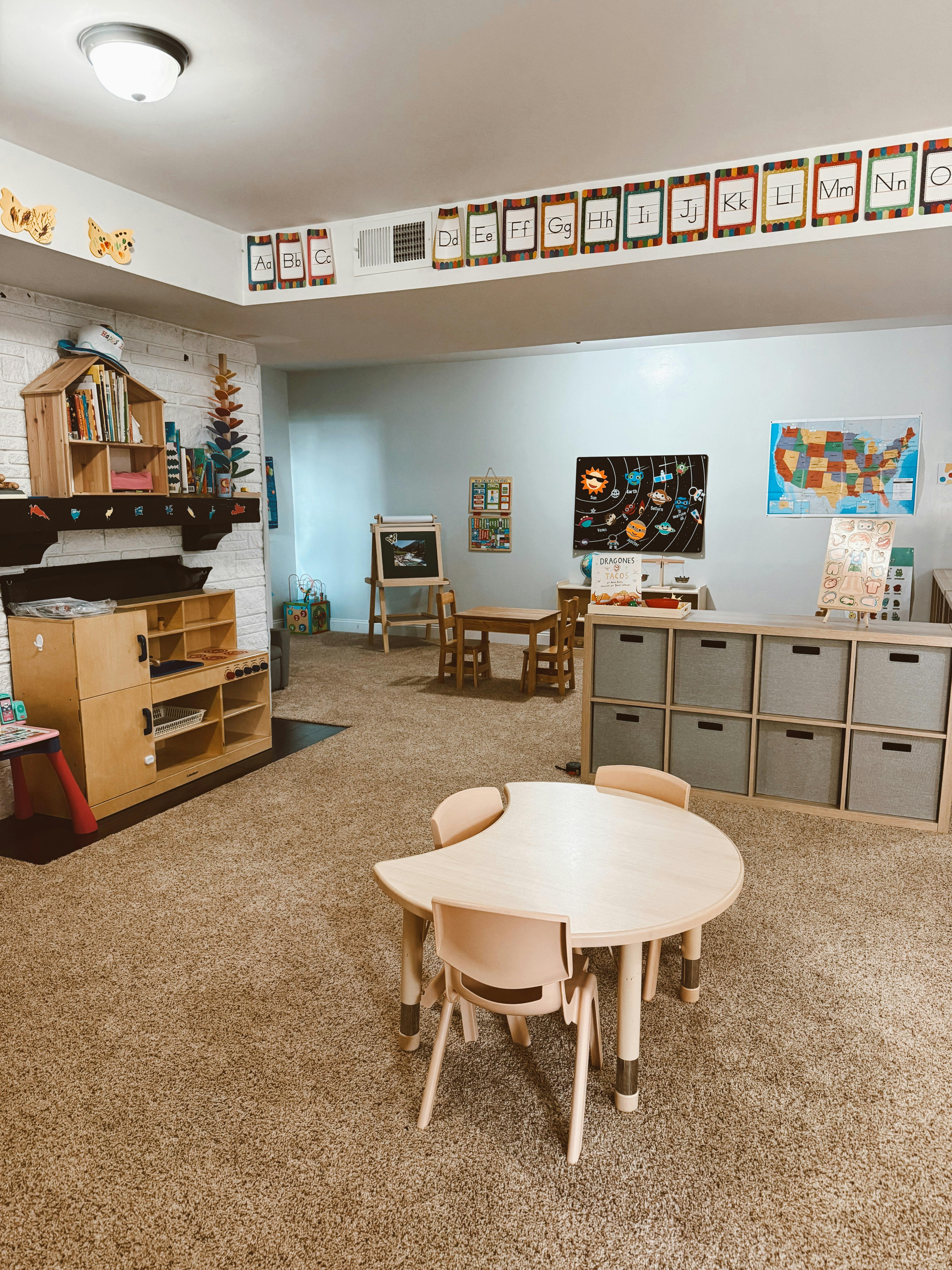 Classroom with small tables and chairs, storage units, and educational posters