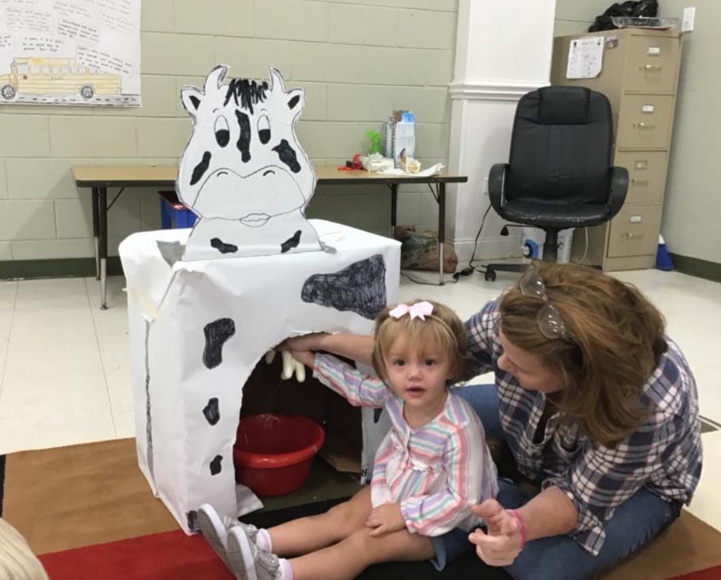 Adult and child playing with a cow-themed activity