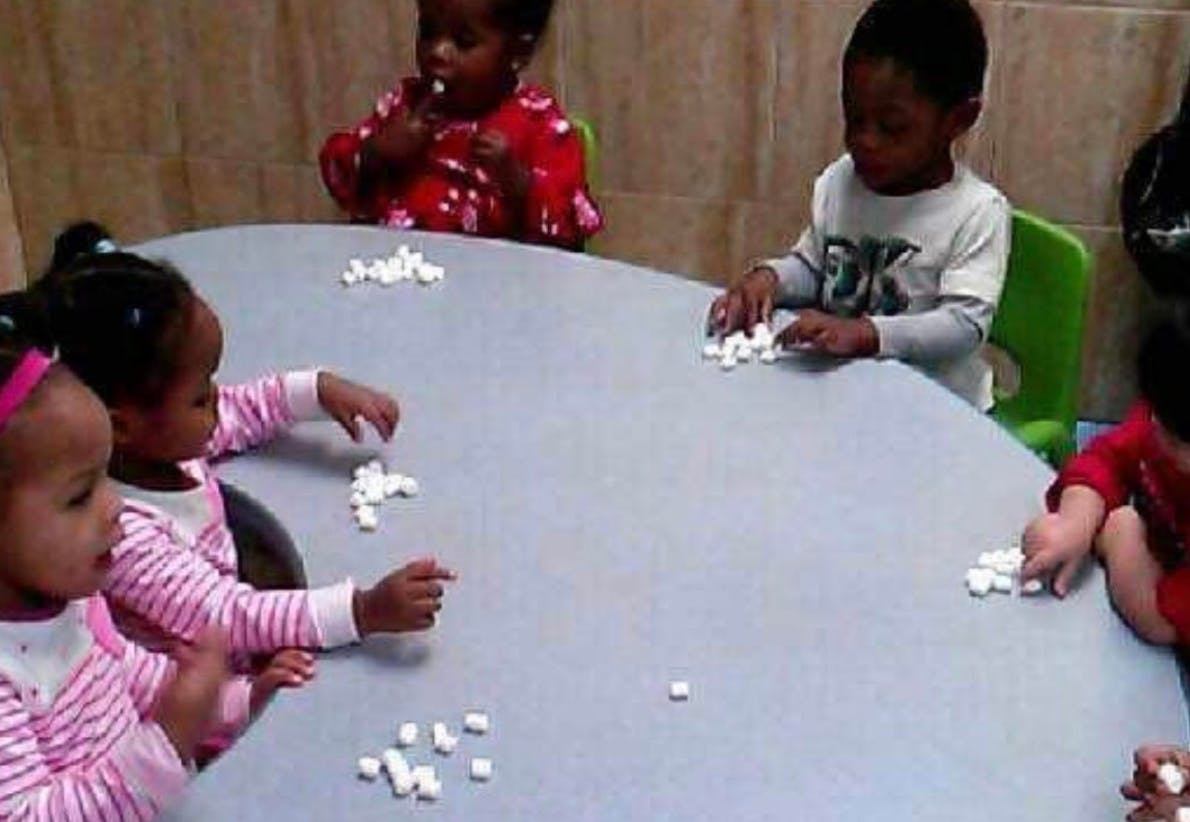Children at a table playing with small white objects