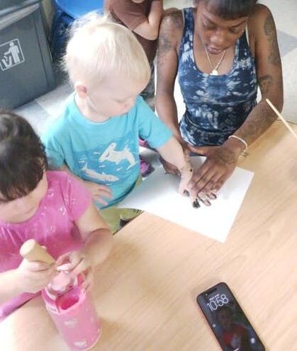 Adult helping a child make a handprint with paint on paper
