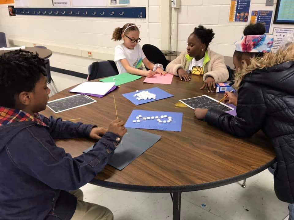 Four children sitting around a table doing crafts