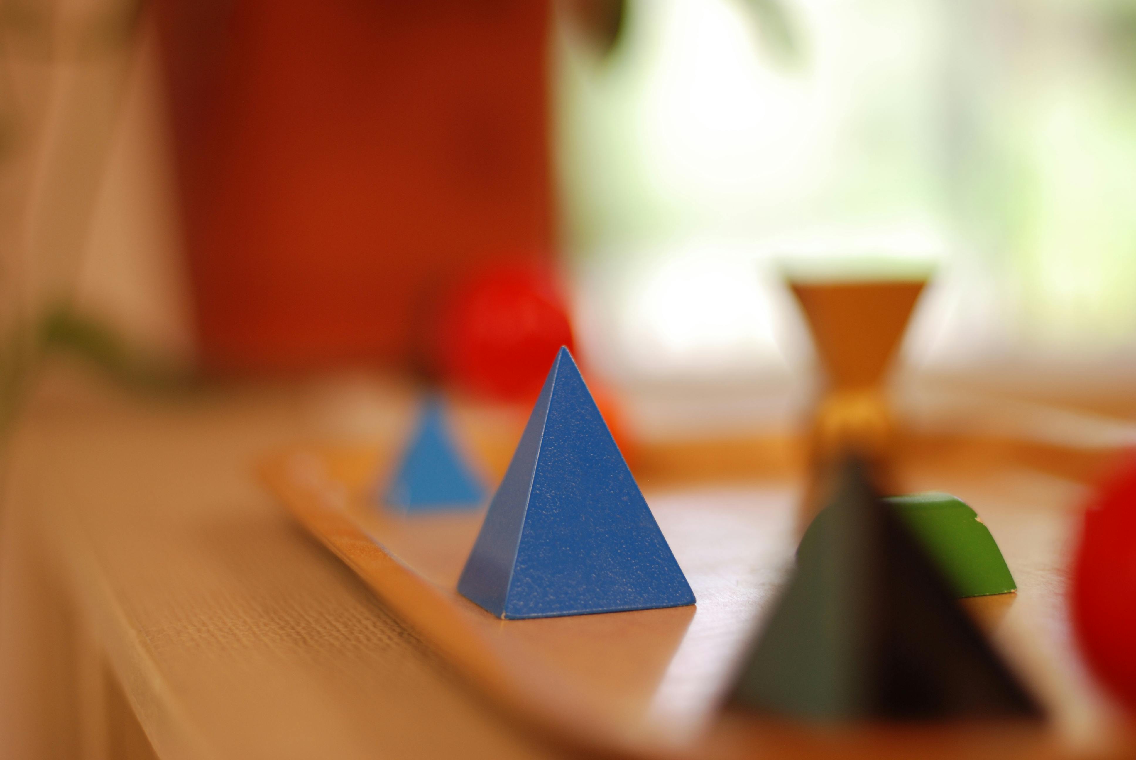 Blue pyramid shape in focus with other shapes in background