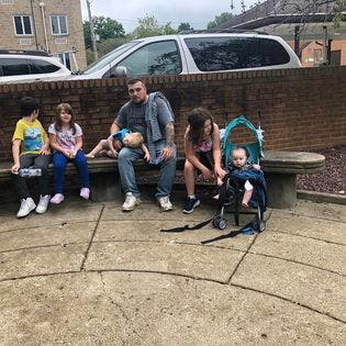 Adults and children sitting on a stone bench