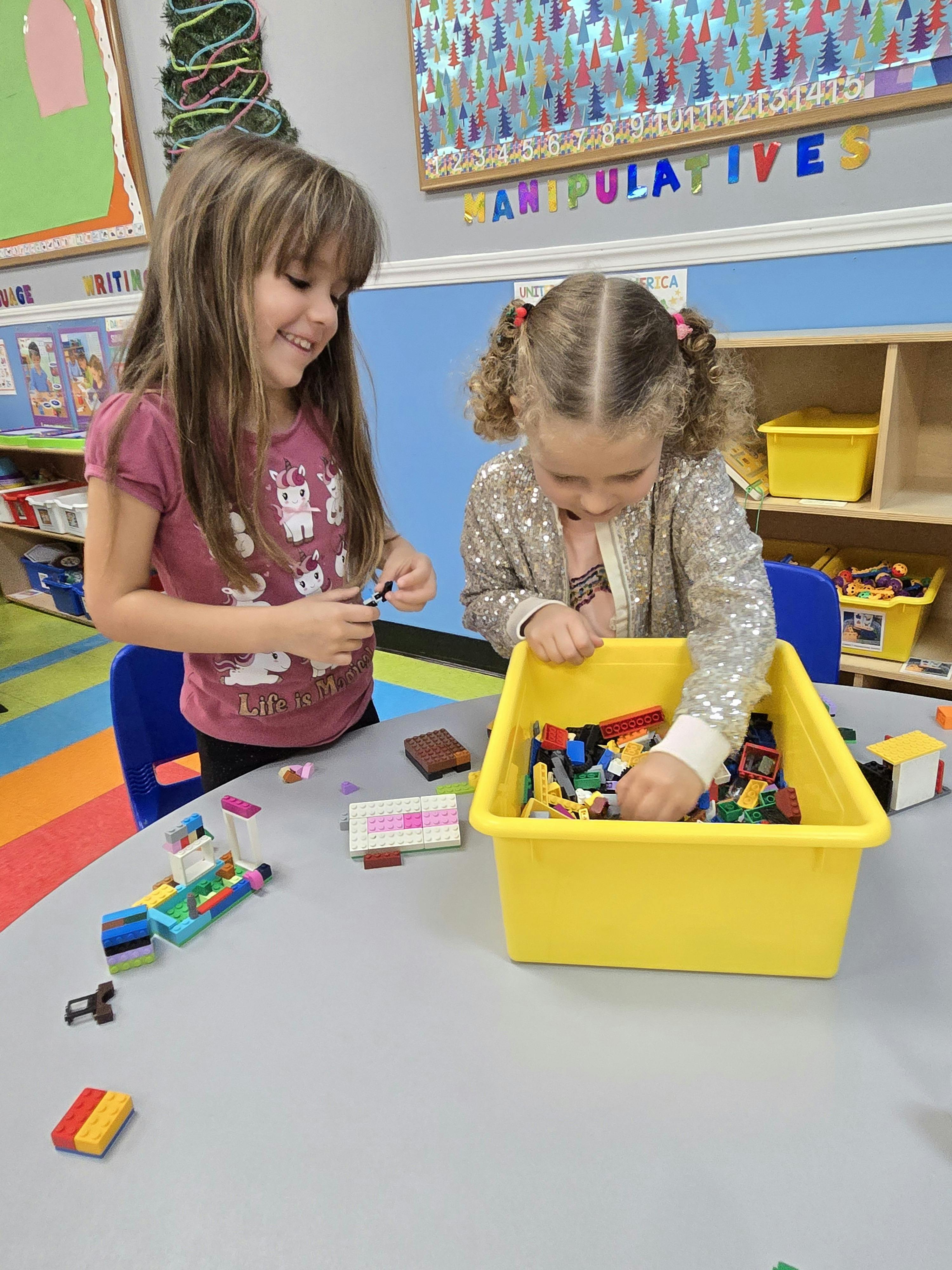 Two children playing with building blocks at a table in a classroom
