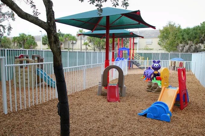 Outdoor playground with slides, play structures, and shade umbrellas