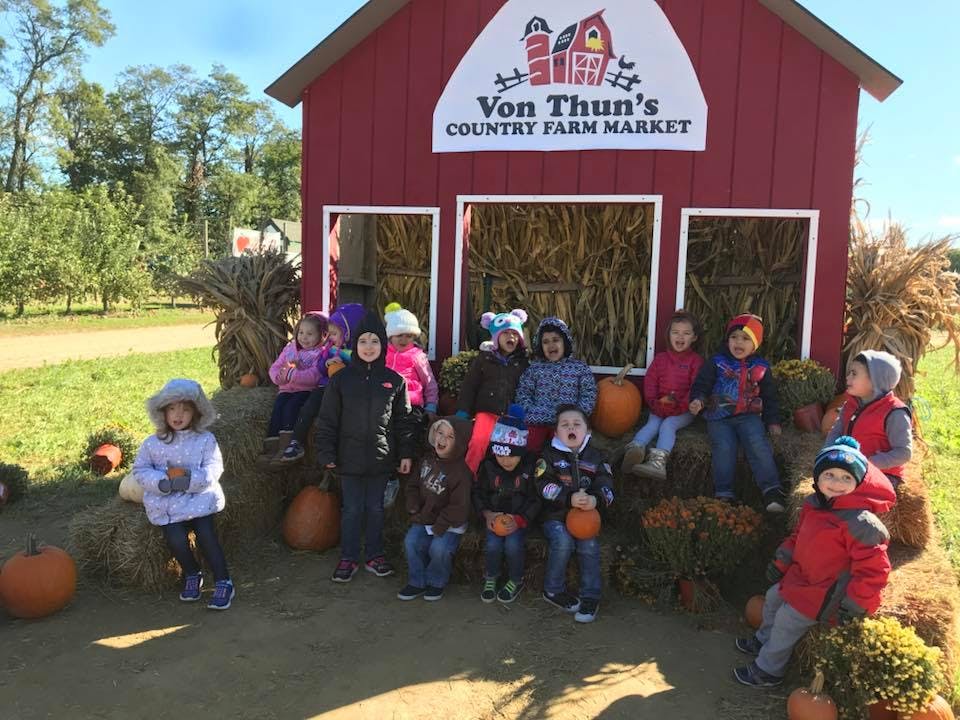 Children posing in front of a red barn with a sign that says Von Thun's Country Farm Market